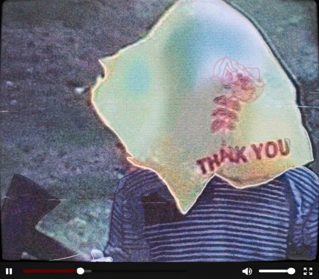FEBRUARY 1997 VHS RIP A photo of an unknown person standing in front of the camera, holding an axe. There is a yellow plastic bag over their head with a red text and a rose that reads "THANK YOU". There is VHS grain on the photo.